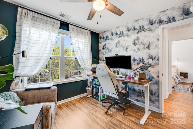 office area featuring visible vents, wood finished floors, baseboards, ceiling fan, and wallpapered walls