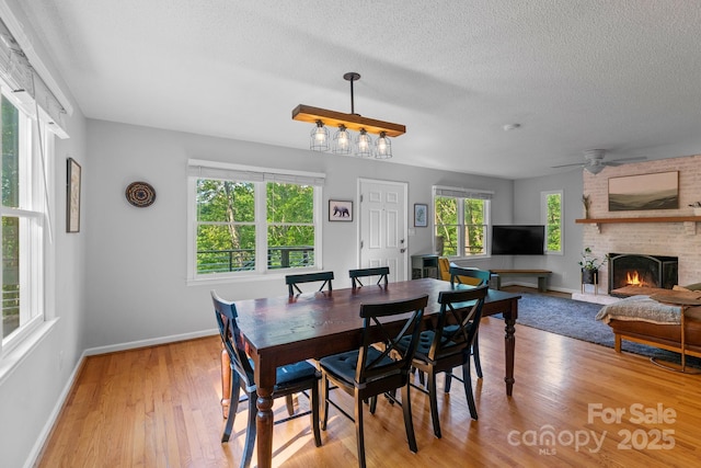 14 Leisure Ln, Weaverville, NC 28787 - dining room featuring light wood finished floors, a textured ceiling, a brick fireplace, and ceiling fan