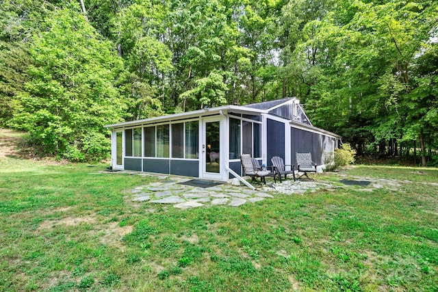 back of property with a sunroom and a yard