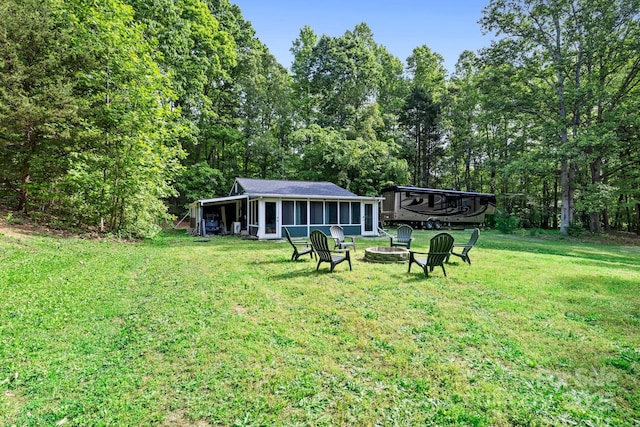 view of grassy yard with an outdoor fire pit and a sunroom
