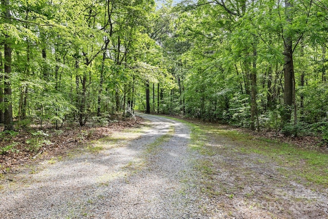 view of dirt / gravel road featuring a wooded view