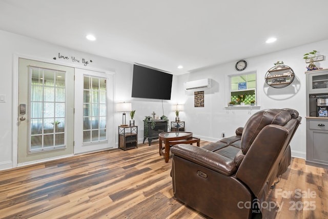living room featuring wood finished floors, an AC wall unit, recessed lighting, and baseboards