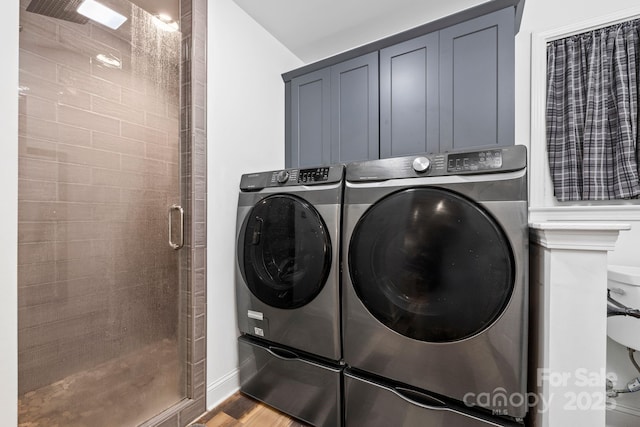 laundry area featuring washing machine and dryer, wood finished floors, cabinet space, and baseboards