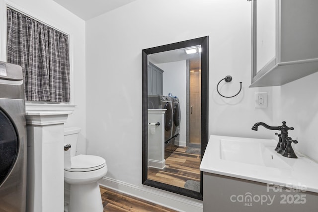bathroom with wood finished floors, toilet, vanity, baseboards, and washer / clothes dryer