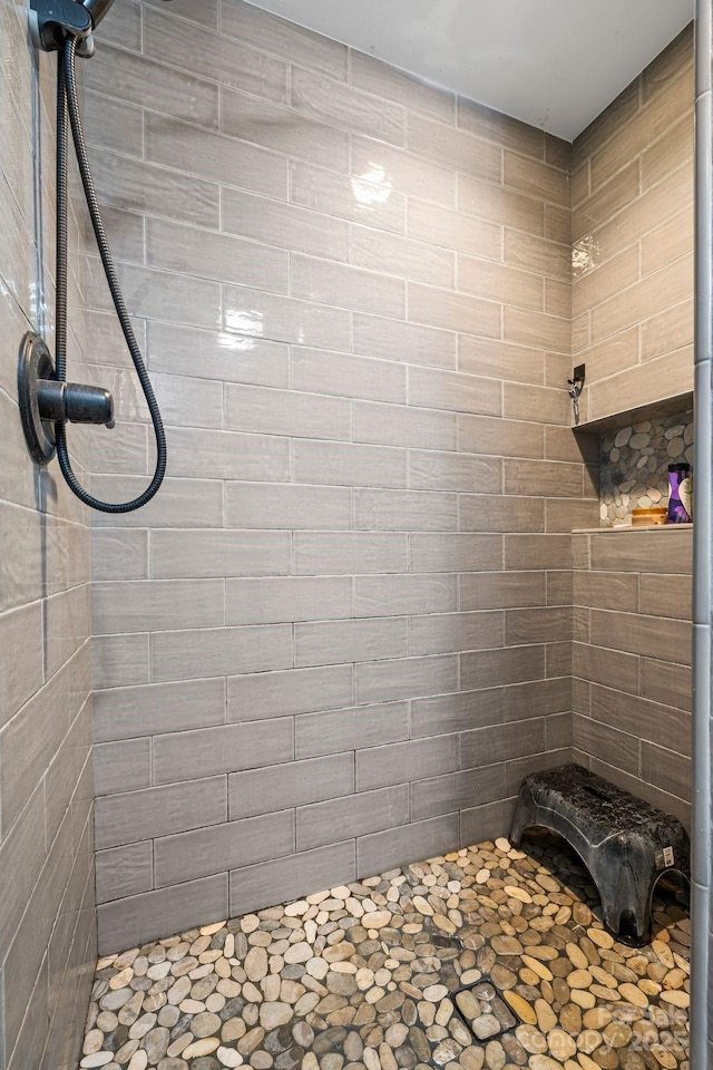 bathroom with tiled shower and stone finish floors