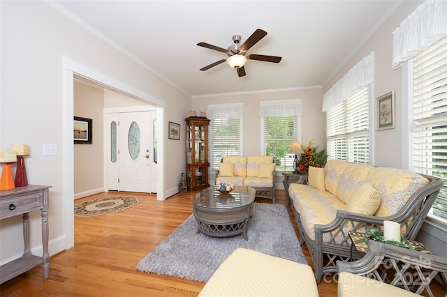 living area featuring ceiling fan, ornamental molding, baseboards, and light wood finished floors
