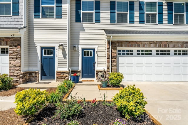 view of exterior entry featuring a garage, driveway, and stone siding