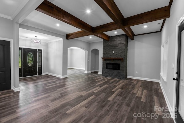 2694 Woodcrest Dr SW, Concord, NC 28027 - unfurnished living room featuring dark wood-style flooring, beam ceiling, arched walkways, a stone fireplace, and baseboards