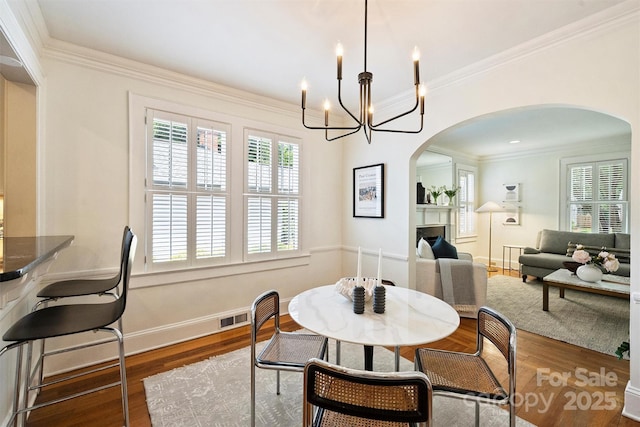 2015 Club Rd, Charlotte, NC 28205 - dining area featuring visible vents, arched walkways, wood finished floors, an inviting chandelier, and ornamental molding