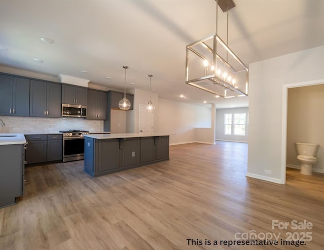 kitchen featuring backsplash, a center island, light countertops, open floor plan, and stainless steel appliances