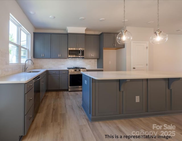 kitchen featuring gray cabinets, a sink, light countertops, light wood-style floors, and stainless steel appliances
