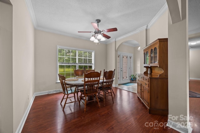 dining area with arched walkways, crown molding, a textured ceiling, dark wood-type flooring, and a ceiling fan