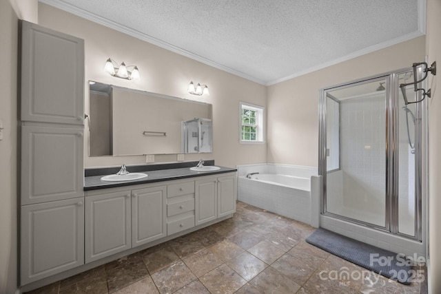 bathroom featuring a textured ceiling, crown molding, a garden tub, a shower stall, and double vanity