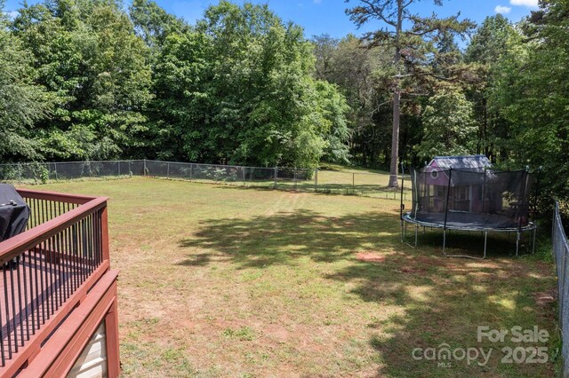 view of yard with a trampoline and view of scattered trees