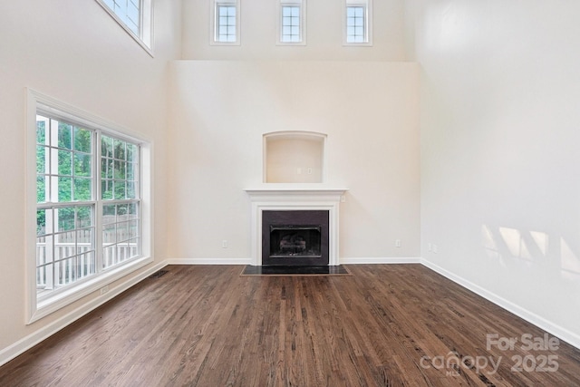 5745 Snapdragon Ln, Huntersville, NC 28078 - unfurnished living room featuring baseboards, a fireplace with flush hearth, a towering ceiling, and dark wood-style floors