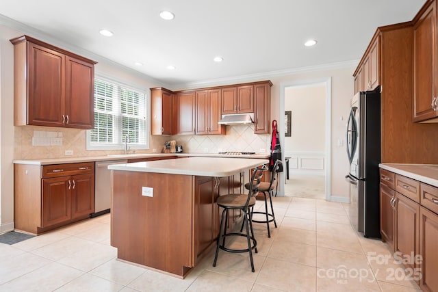 7525 Blackgum Falls Ct, Huntersville, NC 28078 - kitchen with crown molding, appliances with stainless steel finishes, a breakfast bar, under cabinet range hood, and a kitchen island