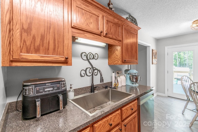 1800 Oriole Ct, Monroe, NC 28112 - kitchen with dark countertops, a sink, dishwasher, a textured ceiling, and brown cabinetry