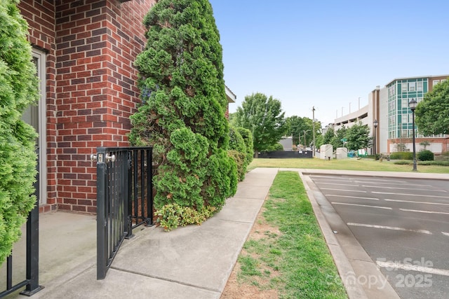 exterior space with a gate, curbs, and sidewalks