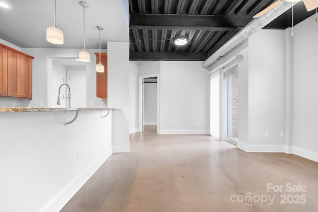 kitchen featuring brown cabinets, concrete floors, baseboards, a breakfast bar, and a sink