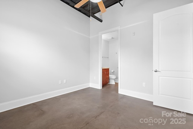 unfurnished bedroom featuring concrete flooring, baseboards, ensuite bath, and ceiling fan