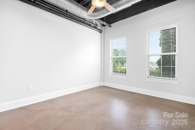 unfurnished room featuring finished concrete flooring, baseboards, and ceiling fan