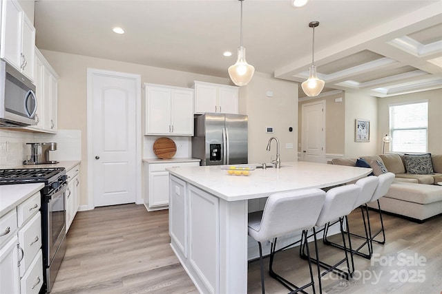 kitchen with recessed lighting, open floor plan, appliances with stainless steel finishes, and a kitchen bar