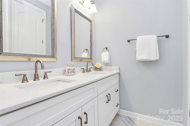 full bath with a sink, baseboards, double vanity, and marble finish floor