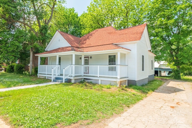 view of front of home featuring a porch, a shingled roof, a front yard, and concrete driveway