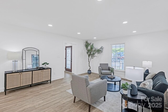 living room with recessed lighting, baseboards, and light wood-style flooring