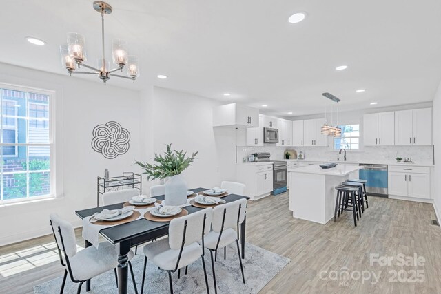 dining room featuring recessed lighting, light wood-style floors, baseboards, and a chandelier