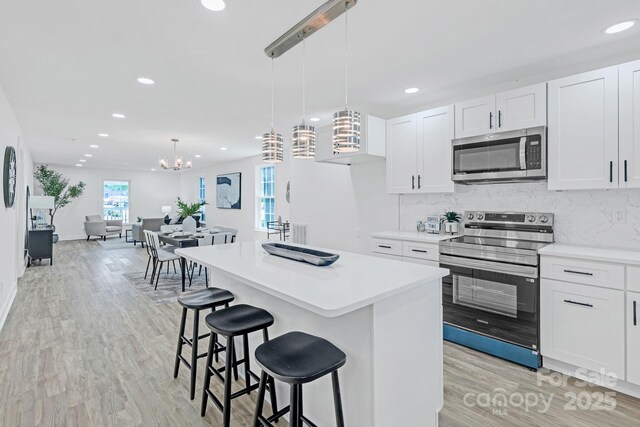 kitchen with a kitchen island, stainless steel appliances, recessed lighting, and light wood finished floors