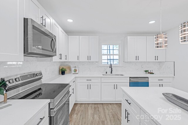 kitchen featuring light countertops, white cabinetry, a sink, appliances with stainless steel finishes, and backsplash