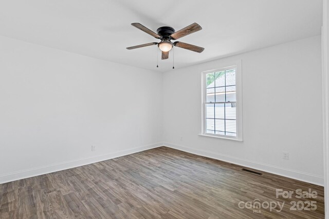 empty room with visible vents, a ceiling fan, baseboards, and wood finished floors