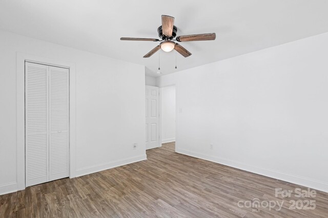 unfurnished bedroom with baseboards, a ceiling fan, wood finished floors, and a closet
