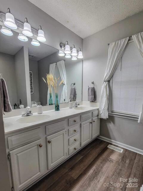 6231 Kentwood Dr, Kannapolis, NC 28081 - full bathroom with double vanity, wood finished floors, and a textured ceiling