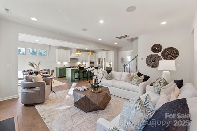 living room featuring recessed lighting, visible vents, stairway, and light wood-style floors