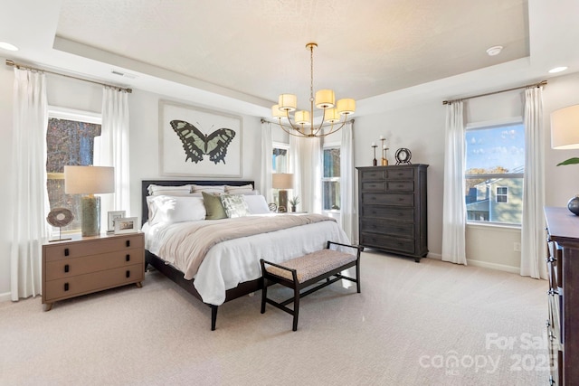 bedroom featuring an inviting chandelier, a raised ceiling, and light colored carpet