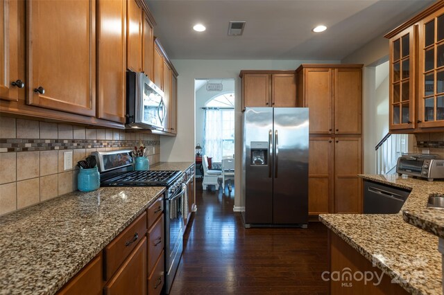 3186 Helmsley Ct, Concord, NC 28027 - kitchen with dark wood-style flooring, light stone counters, brown cabinetry, stainless steel appliances, and visible vents