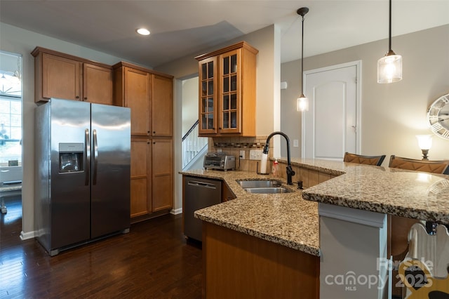 3186 Helmsley Ct, Concord, NC 28027 - kitchen featuring dark wood-style flooring, light stone countertops, brown cabinets, a sink, and stainless steel appliances