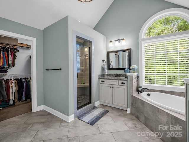 full bathroom featuring a healthy amount of sunlight, a walk in closet, vaulted ceiling, and a stall shower