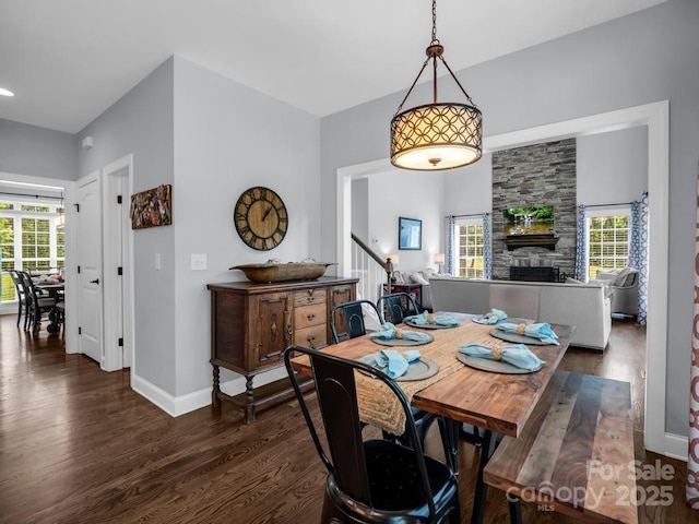 dining room with dark wood-style flooring, baseboards, a healthy amount of sunlight, and a fireplace