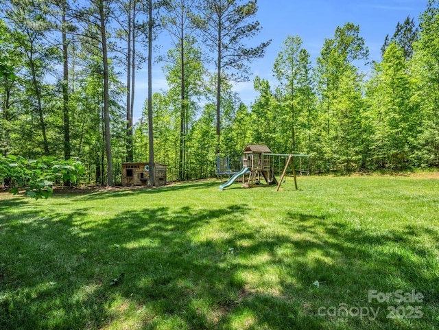 view of yard featuring an outdoor structure, a playground, and a shed