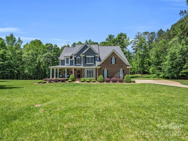 view of front of home with a porch, brick siding, and a front lawn