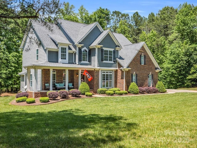 craftsman-style house with a shingled roof, brick siding, and a front yard