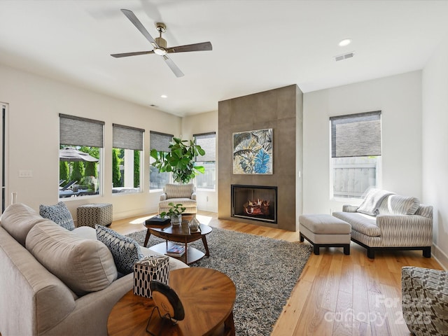 living room with visible vents, wood finished floors, a healthy amount of sunlight, and a tile fireplace