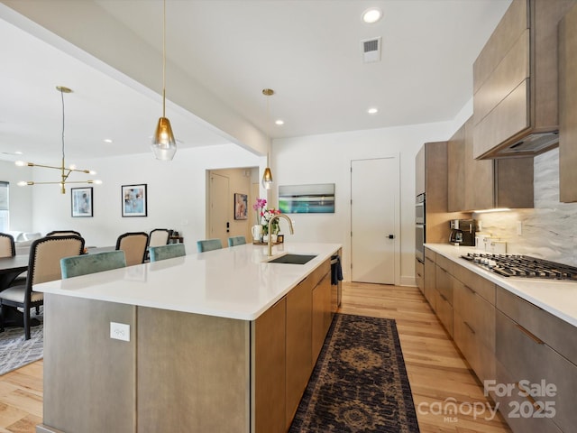 kitchen featuring visible vents, modern cabinets, a spacious island, a sink, and stainless steel gas stovetop