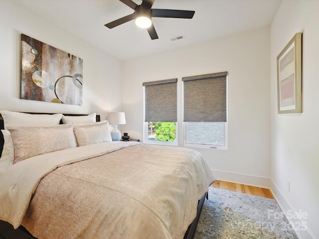 bedroom featuring visible vents, a ceiling fan, baseboards, and wood finished floors