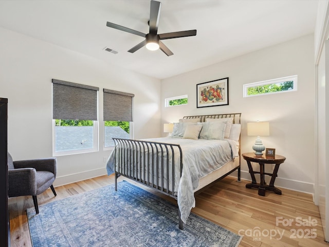 bedroom with baseboards, a ceiling fan, wood finished floors, and visible vents