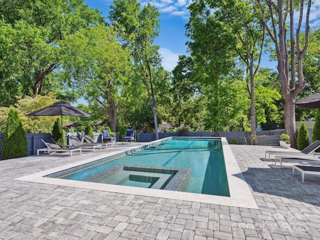view of swimming pool with fence, a pool with connected hot tub, and a patio area