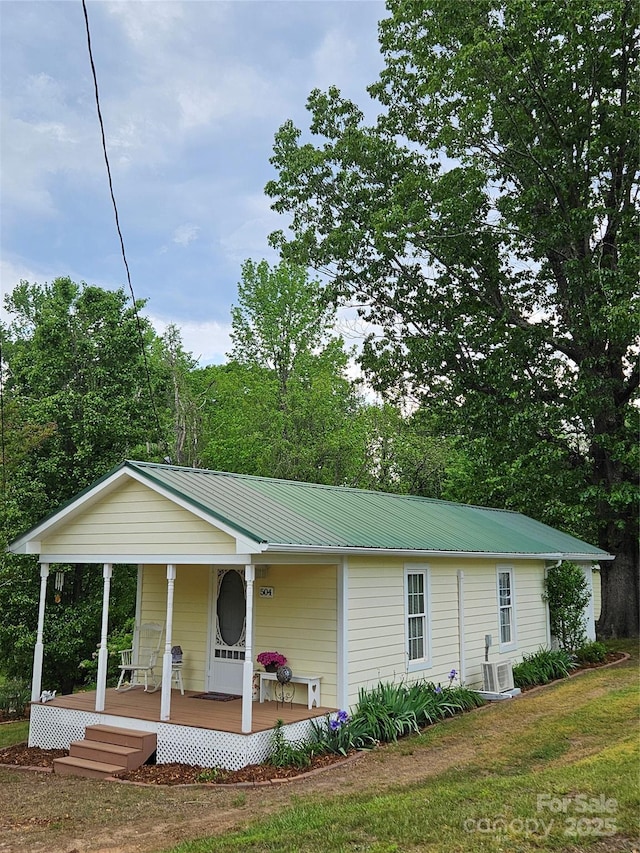 back of property with a porch, a yard, and metal roof